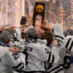 Players lifting NCAA Frozen Four championship trophy in celebration after the final game